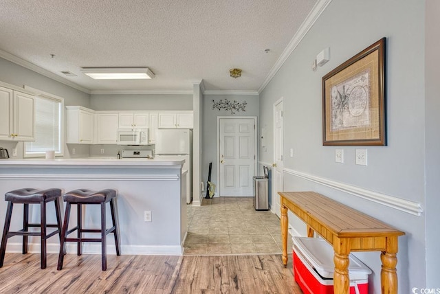 kitchen featuring white cabinets, white appliances, light hardwood / wood-style flooring, a kitchen breakfast bar, and crown molding