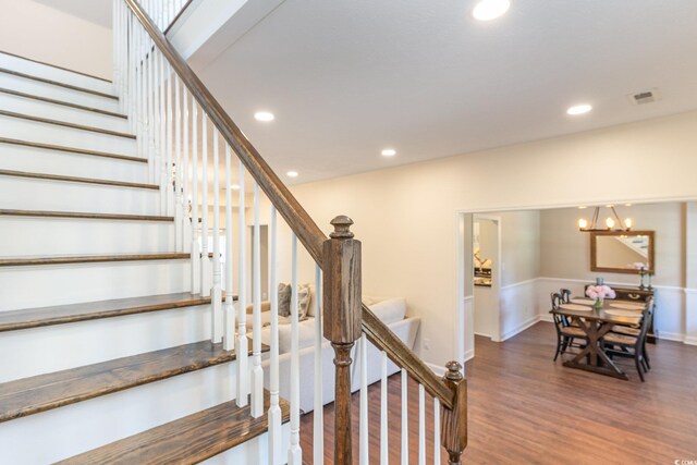 stairway featuring hardwood / wood-style floors and an inviting chandelier