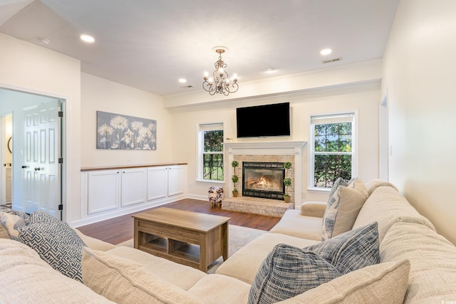 living room featuring visible vents, a healthy amount of sunlight, a glass covered fireplace, and wood finished floors