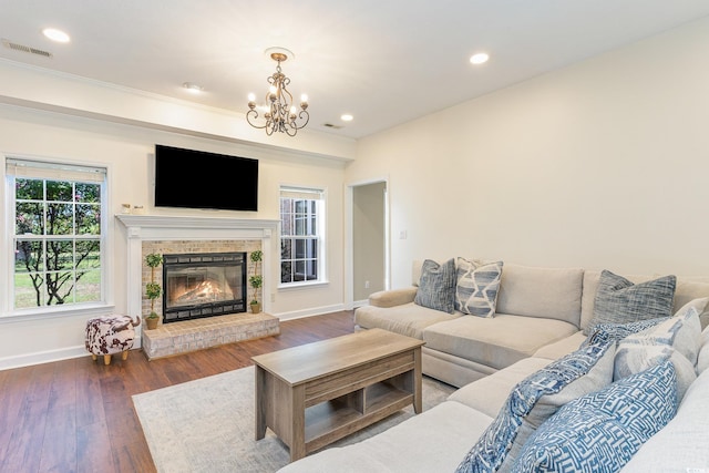 living room featuring visible vents, baseboards, a glass covered fireplace, and wood finished floors