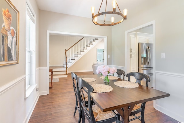 dining room with stairway, wood finished floors, baseboards, and a chandelier