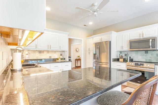 kitchen with stainless steel appliances, a kitchen breakfast bar, tasteful backsplash, and white cabinetry