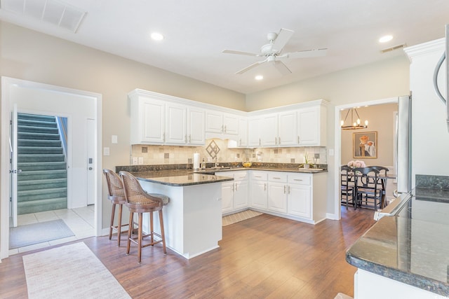 kitchen featuring visible vents, a peninsula, and white cabinetry