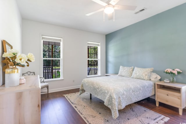 bedroom featuring visible vents, a ceiling fan, dark wood-type flooring, and baseboards