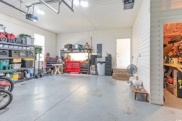 garage with electric panel, a workshop area, a garage door opener, and metal wall