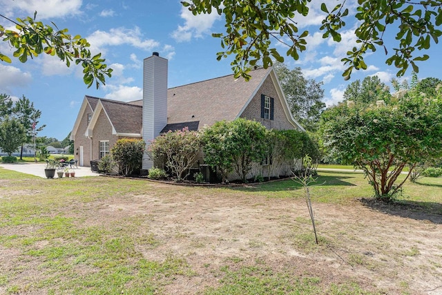 view of property exterior featuring a patio area, a lawn, and a chimney