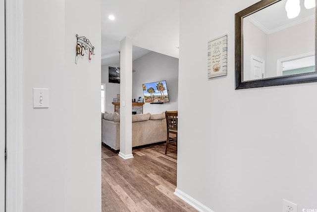 corridor with lofted ceiling, ornamental molding, and hardwood / wood-style floors