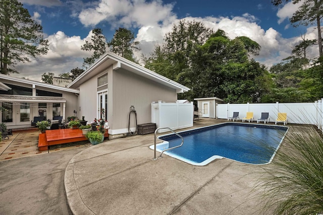 view of pool featuring french doors, a patio, and a shed