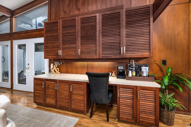 office featuring light hardwood / wood-style flooring, wood walls, built in desk, and vaulted ceiling with beams