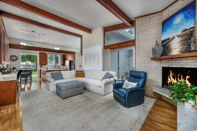 living room with sink, a fireplace, beam ceiling, and hardwood / wood-style floors