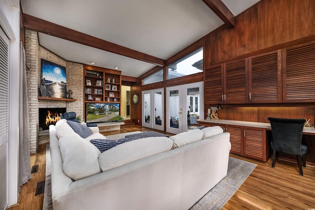 living room featuring light wood-type flooring, vaulted ceiling with beams, a wealth of natural light, and a brick fireplace