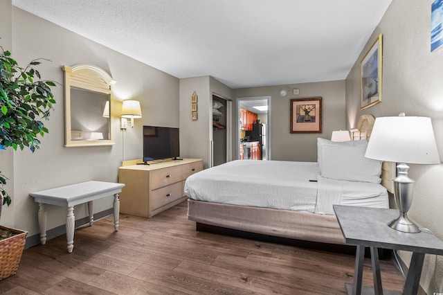 bedroom featuring dark hardwood / wood-style floors, a textured ceiling, a spacious closet, and a closet