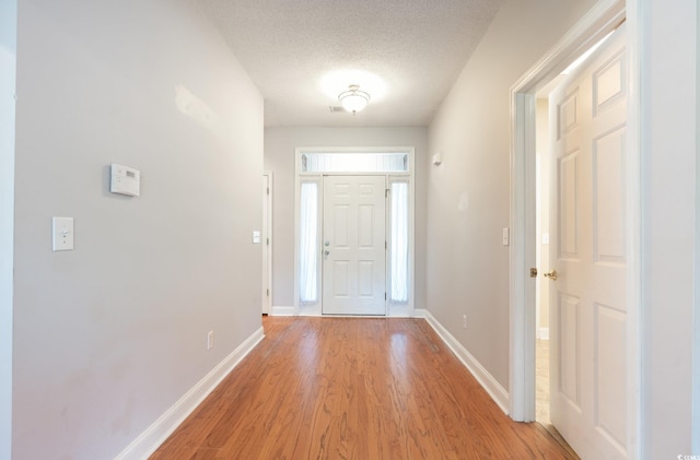 foyer entrance featuring a textured ceiling and light wood-type flooring