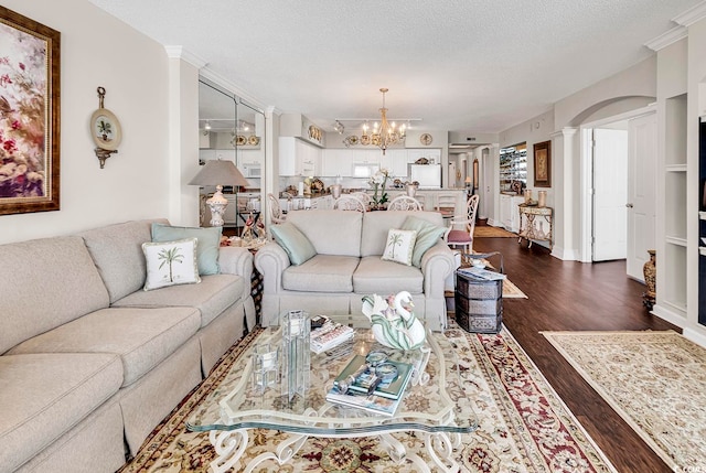 living room with a textured ceiling, an inviting chandelier, and dark hardwood / wood-style floors