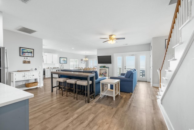 living room with wood-type flooring and ceiling fan with notable chandelier