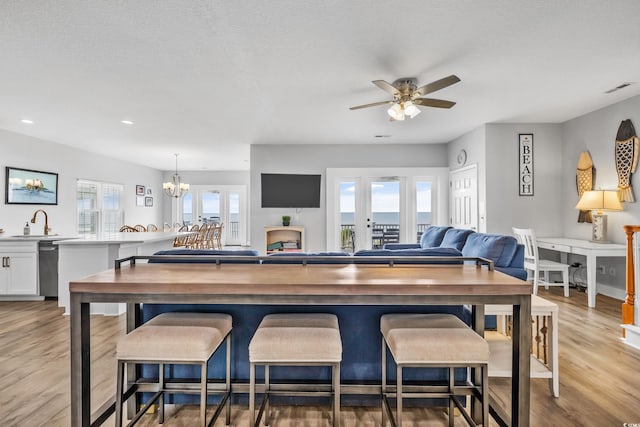 kitchen with light wood-type flooring, a healthy amount of sunlight, white cabinetry, and a breakfast bar