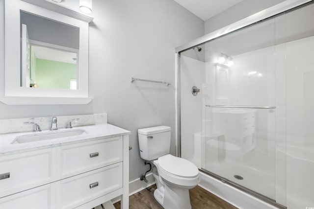 bathroom featuring hardwood / wood-style floors, vanity, a shower with door, and toilet