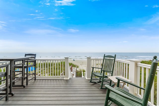 wooden terrace featuring a view of the beach and a water view