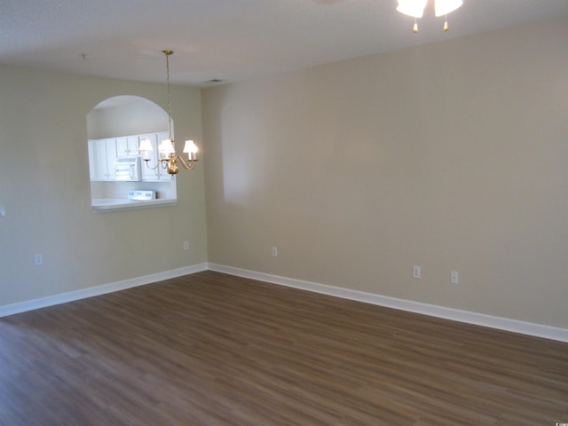 unfurnished room featuring dark hardwood / wood-style flooring and a notable chandelier