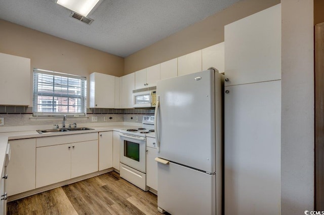 kitchen featuring a wealth of natural light, sink, light hardwood / wood-style floors, and white appliances