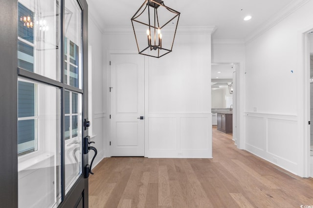 interior space featuring light hardwood / wood-style flooring, ornamental molding, and a notable chandelier