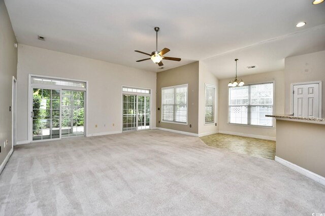 unfurnished living room featuring ceiling fan with notable chandelier and light carpet