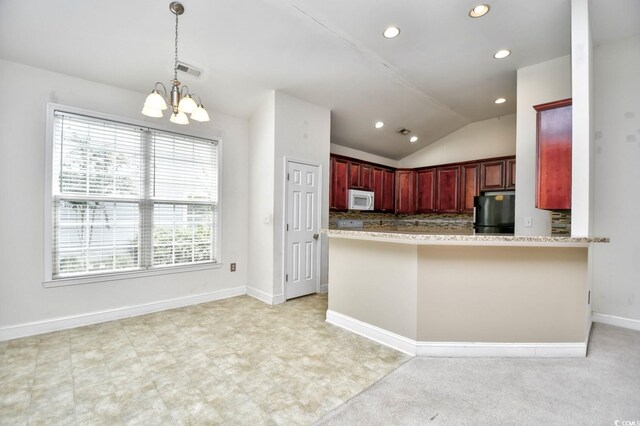 kitchen with vaulted ceiling, black refrigerator, kitchen peninsula, and light tile patterned flooring