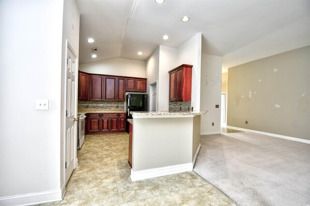 kitchen featuring kitchen peninsula, light stone countertops, decorative backsplash, lofted ceiling, and light tile patterned flooring