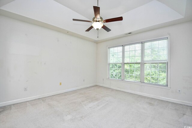 unfurnished room featuring ceiling fan, a raised ceiling, and light carpet