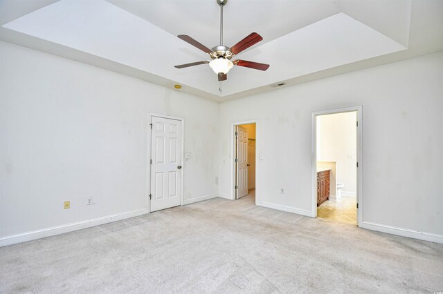 unfurnished bedroom with ceiling fan, ensuite bathroom, and light carpet