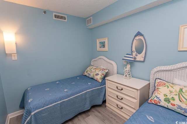 bedroom featuring a textured ceiling and light hardwood / wood-style flooring