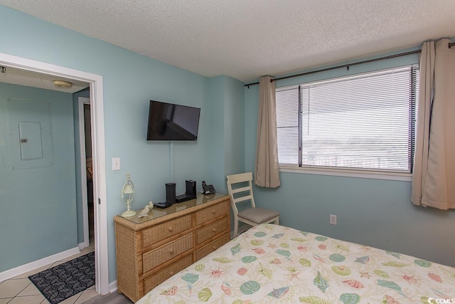 bedroom featuring light tile patterned floors, electric panel, and a textured ceiling