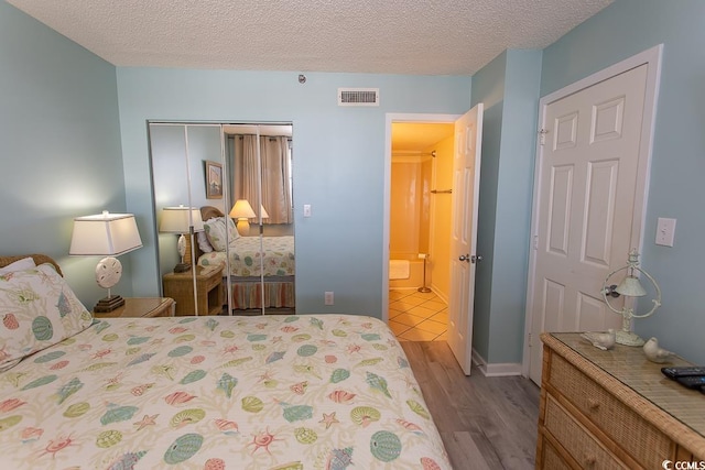 bedroom with a textured ceiling, hardwood / wood-style floors, and a closet