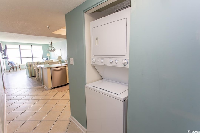 laundry room featuring stacked washer and clothes dryer and light tile patterned flooring