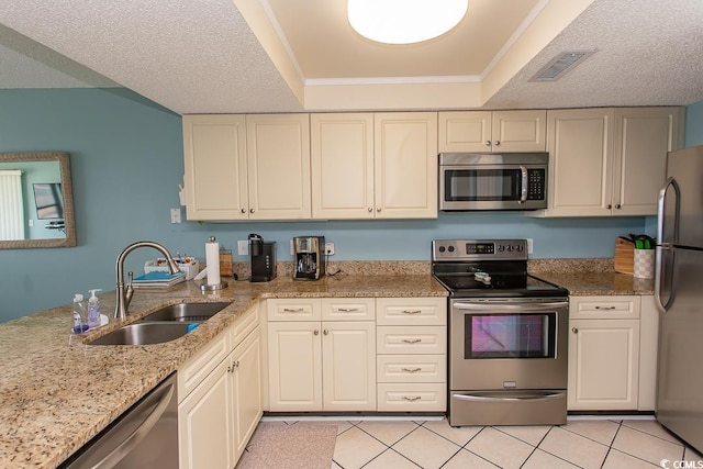 kitchen with light stone counters, light tile patterned floors, stainless steel appliances, and sink