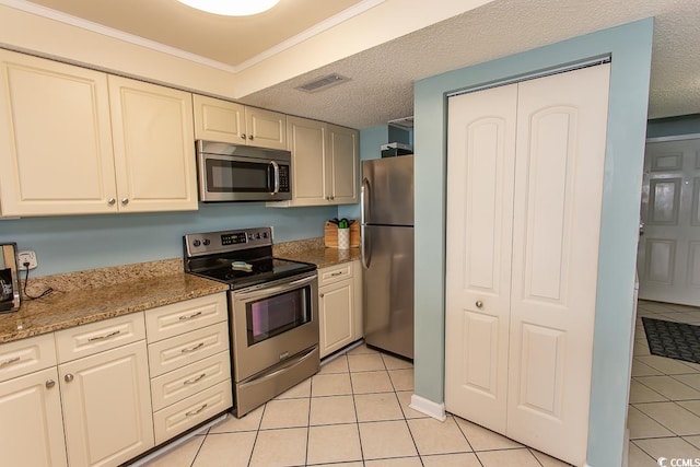 kitchen with ornamental molding, light tile patterned floors, appliances with stainless steel finishes, and stone counters