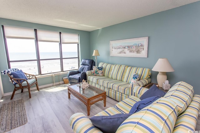 living room with a textured ceiling, light hardwood / wood-style flooring, and a water view