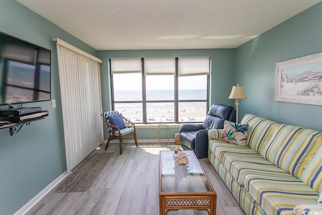 living room with a water view, a textured ceiling, and light hardwood / wood-style flooring