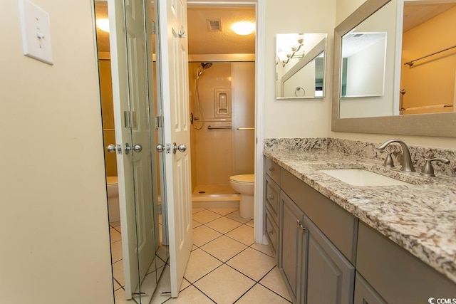 bathroom featuring tile patterned flooring, vanity, toilet, a shower with shower door, and a textured ceiling