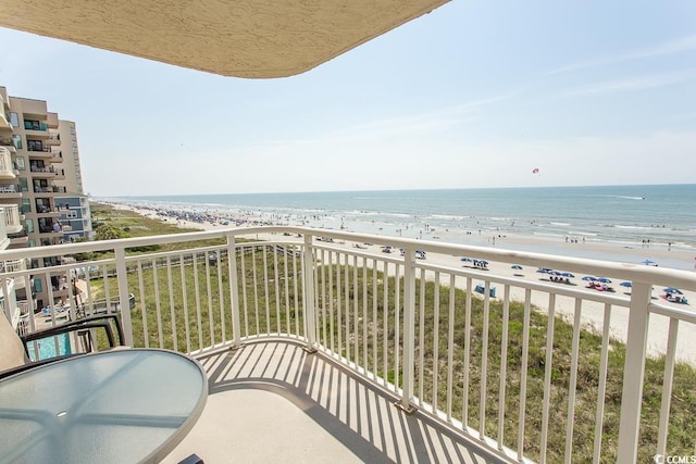 balcony featuring a view of the beach and a water view