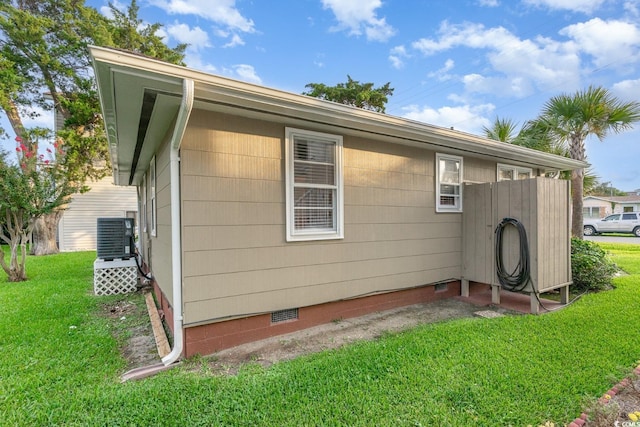 view of side of home with a yard and central AC