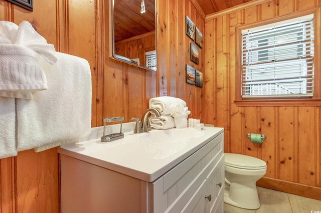 bathroom with vanity, toilet, wooden walls, and tile patterned floors