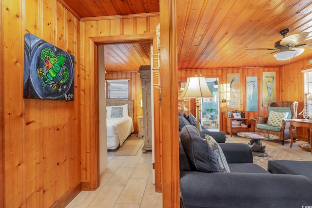 tiled living room featuring ceiling fan, wooden walls, and wooden ceiling