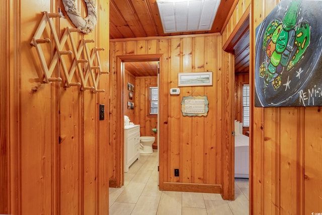 hallway with wood ceiling, light tile patterned floors, and wooden walls