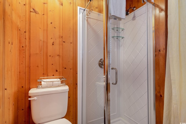 bathroom featuring toilet, an enclosed shower, and wood walls