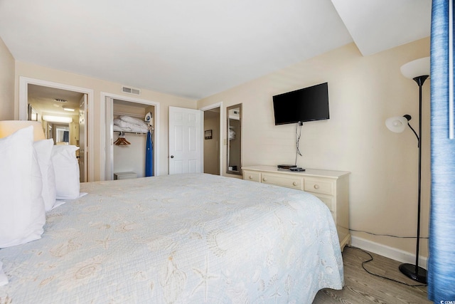 bedroom featuring a walk in closet, a closet, and light hardwood / wood-style flooring