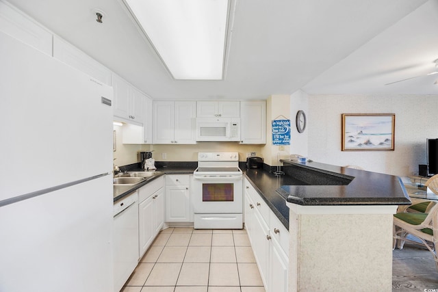 kitchen with white appliances, light tile patterned floors, a peninsula, white cabinetry, and dark countertops