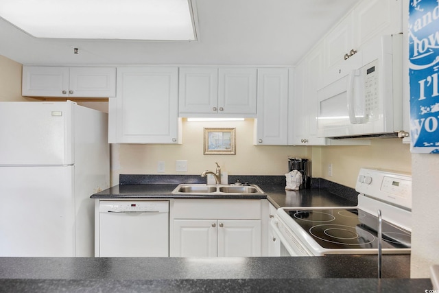 kitchen with white appliances, white cabinets, dark countertops, and a sink