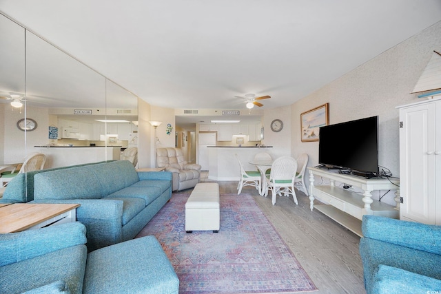 living area featuring wood finished floors, visible vents, and ceiling fan