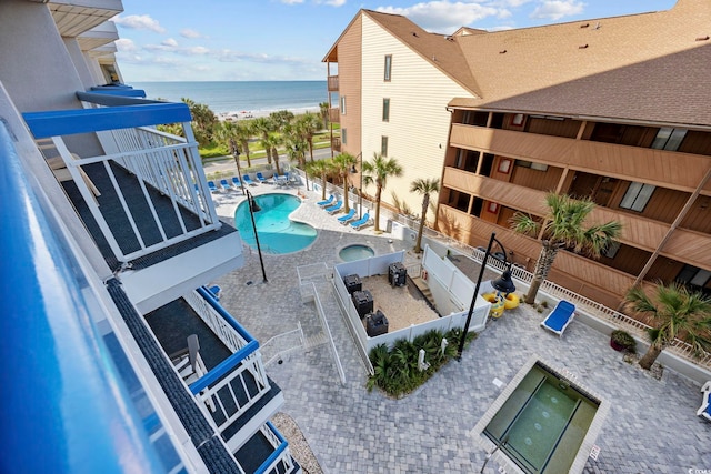 pool with a water view, fence, and a patio area